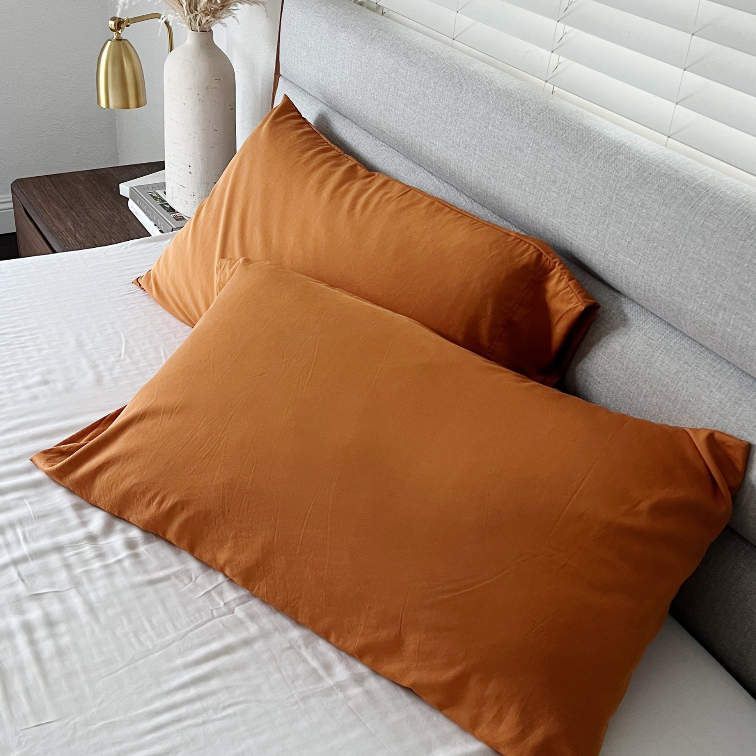 Terracotta Copper Infused Bamboo Pillowcase Set on a white sheet, beside a grey headboard.